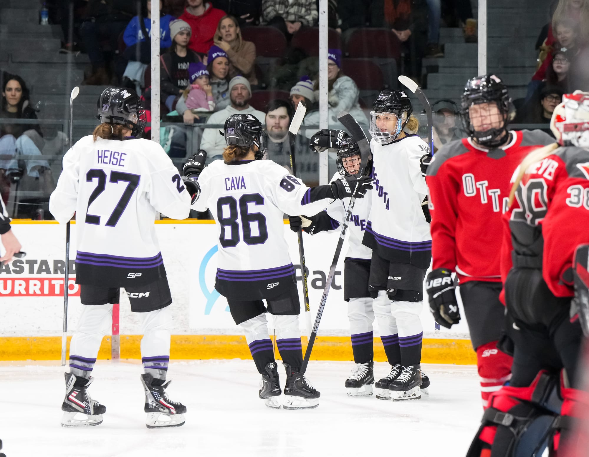 Minnesota players, wearing their white away uniforms, celebrate a goal against Ottawa.