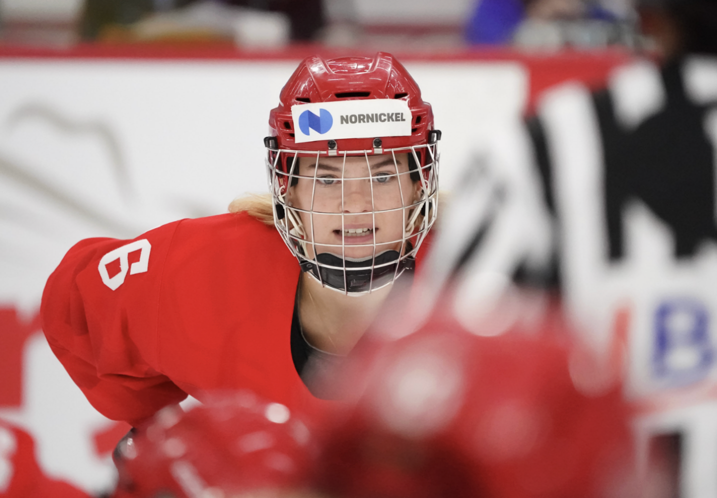 Markova prepares for a faceoff. She is looking towards the camera and wearing a red Russia uniform.