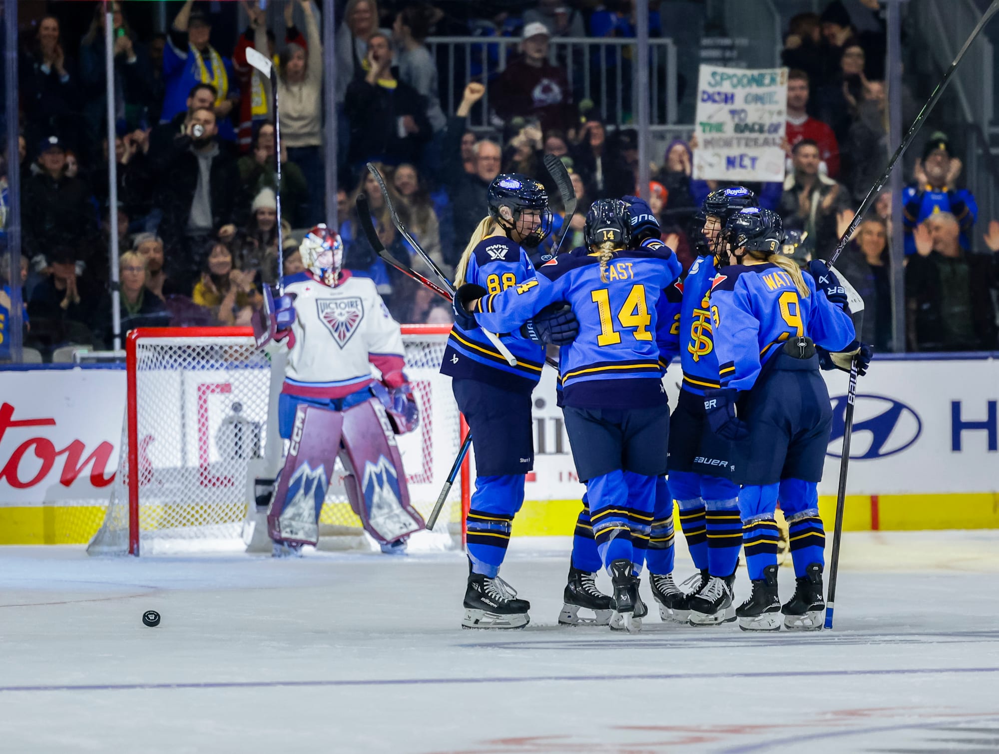 Five Sceptres players celebrate with a group hug near the blue line. They are wearing blue home uniforms.