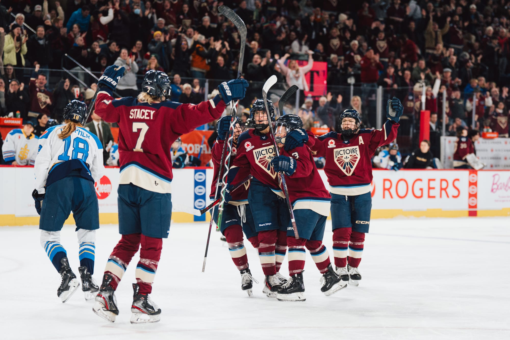Five Montréal players celebrate a goal with a group hug. They are wearing maroon home uniforms.