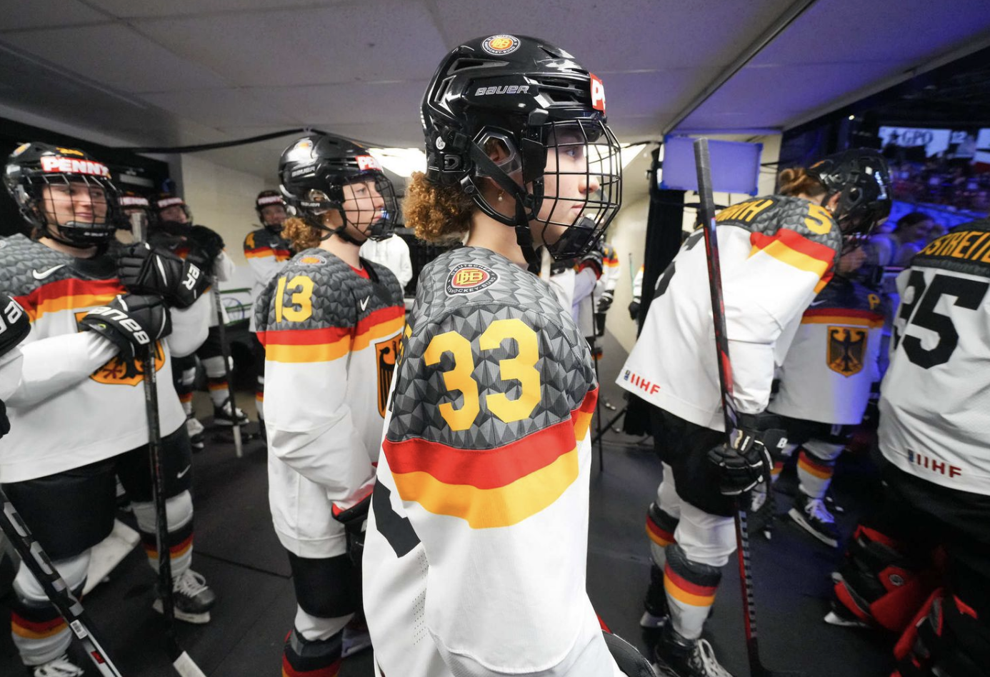 The German national teams walks toward the ice from the locker room. They are all wearing white Germany uniforms.