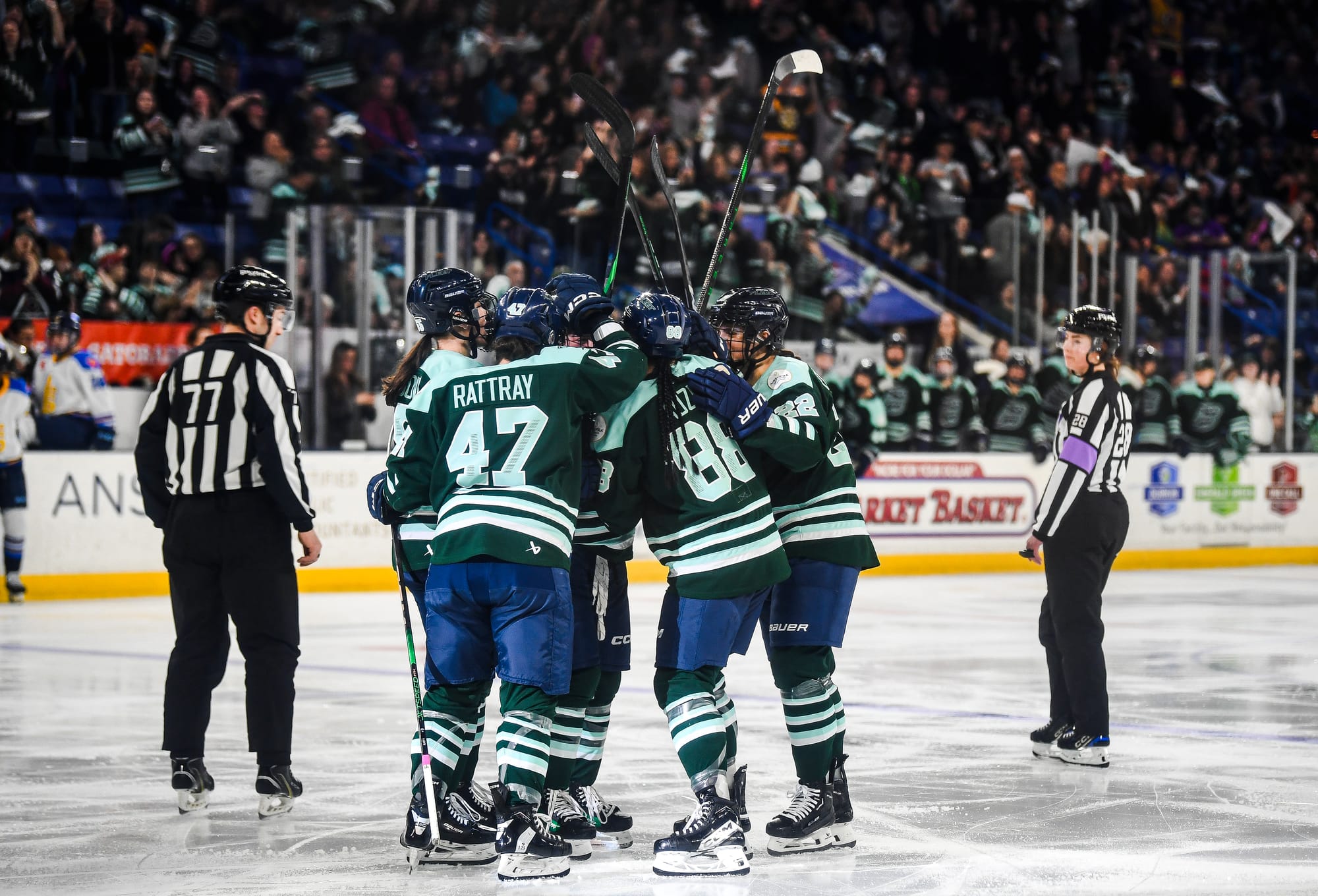 Fleet players celebrate with a tight group hug near the blueline. They are wearing green home uniforms.