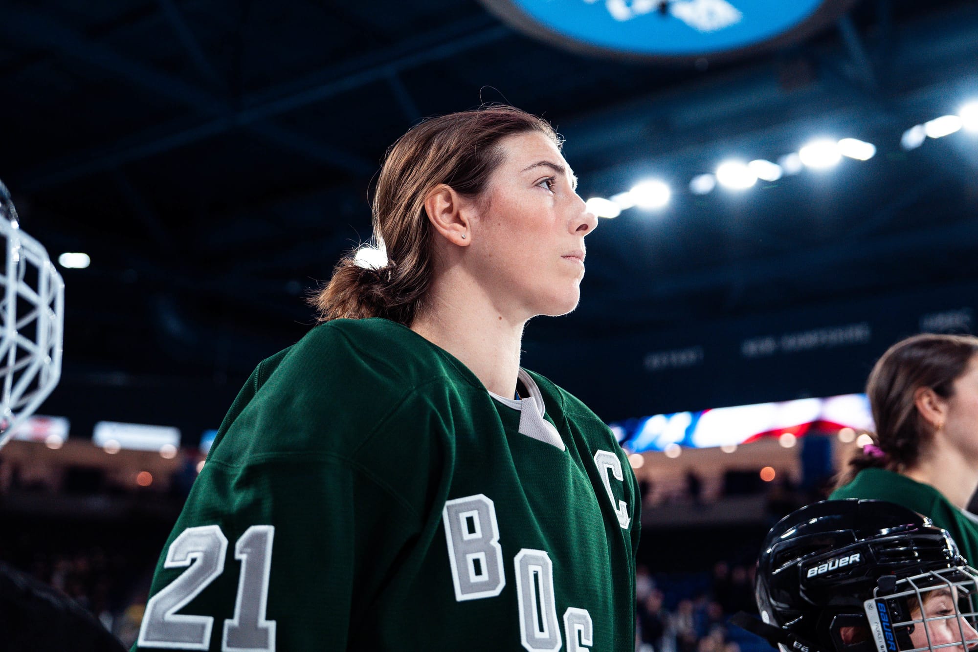 An elbow-up shot of Knight as she gazes at an out-of-frame flag. She is wearing a green Boston home jersey.