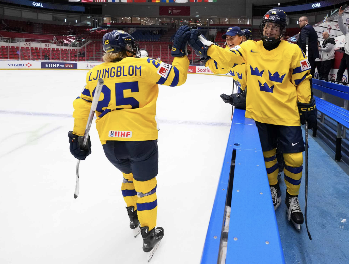 Ljungblom skates down the handshake line at the bench after scoring against Hungary. She is wearing a yellow uniform.