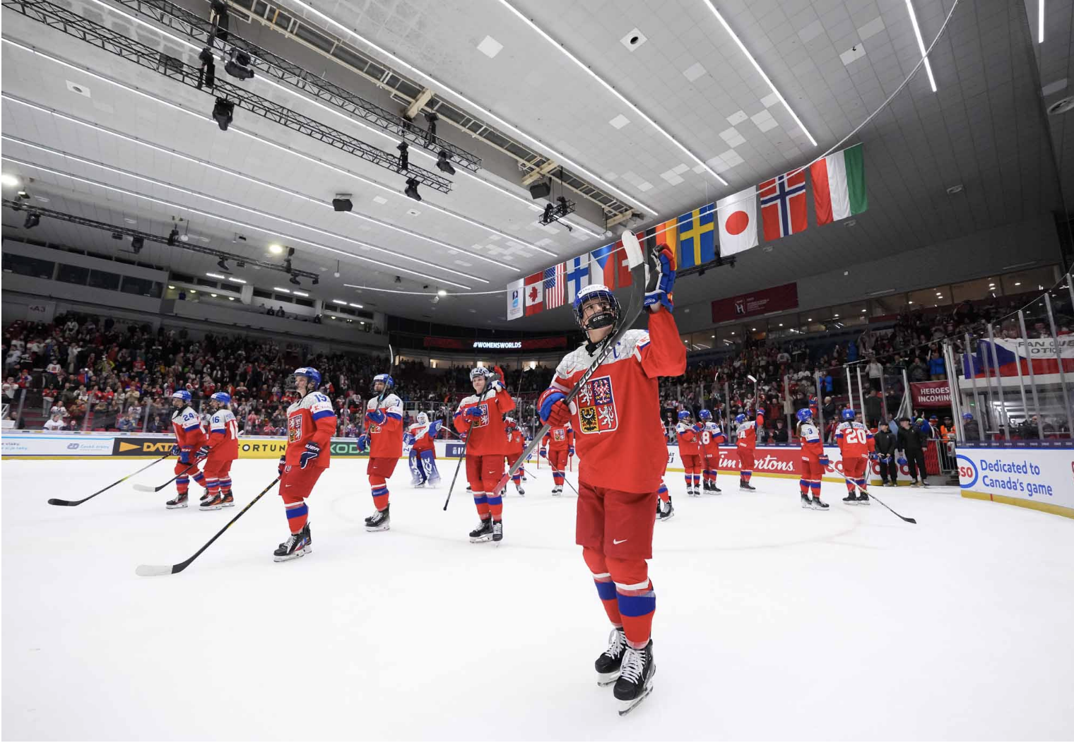 All members of Team Czechia salute the raucous crowd. They are wearing red uniforms.