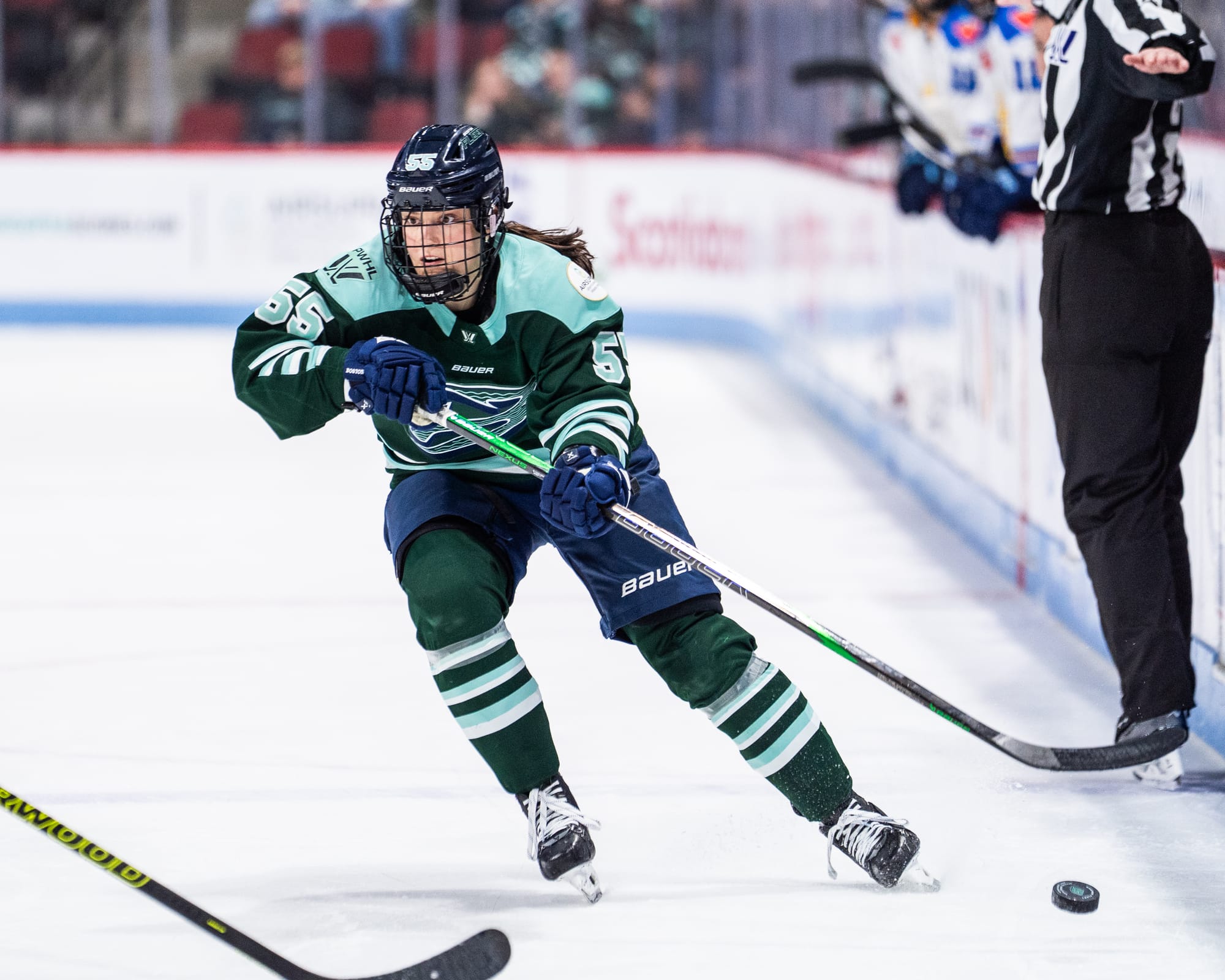 Pejšová looks up as she moves the puck up ice. She is wearing a green home uniform.