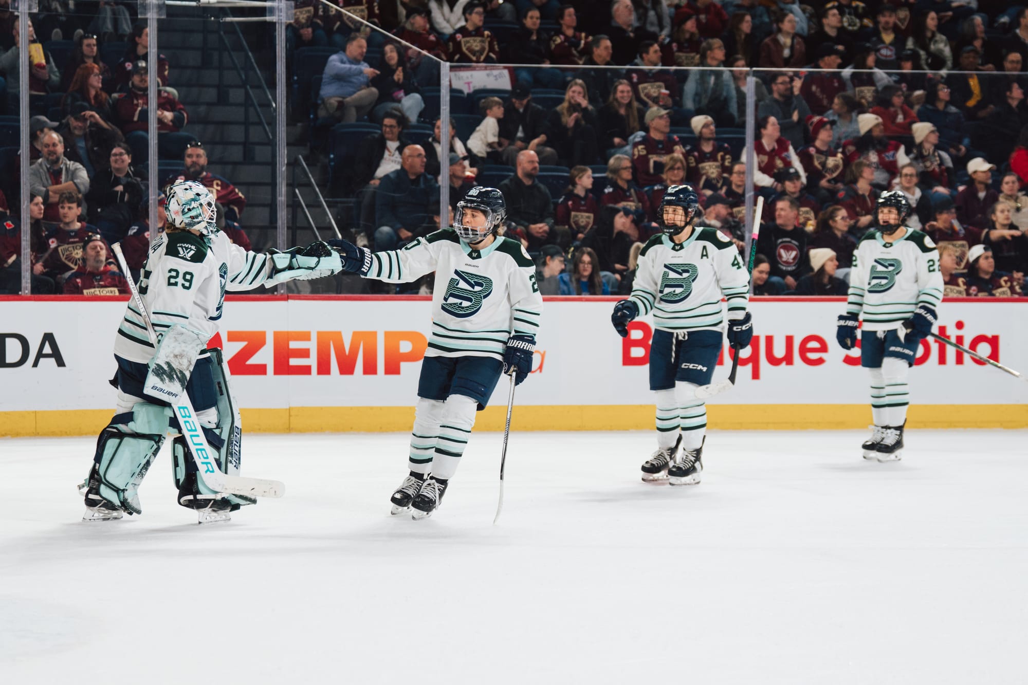 Brandt and Peslarová fist bump as two players line up behind Brandt to do the same. They are all wearing white away uniforms.