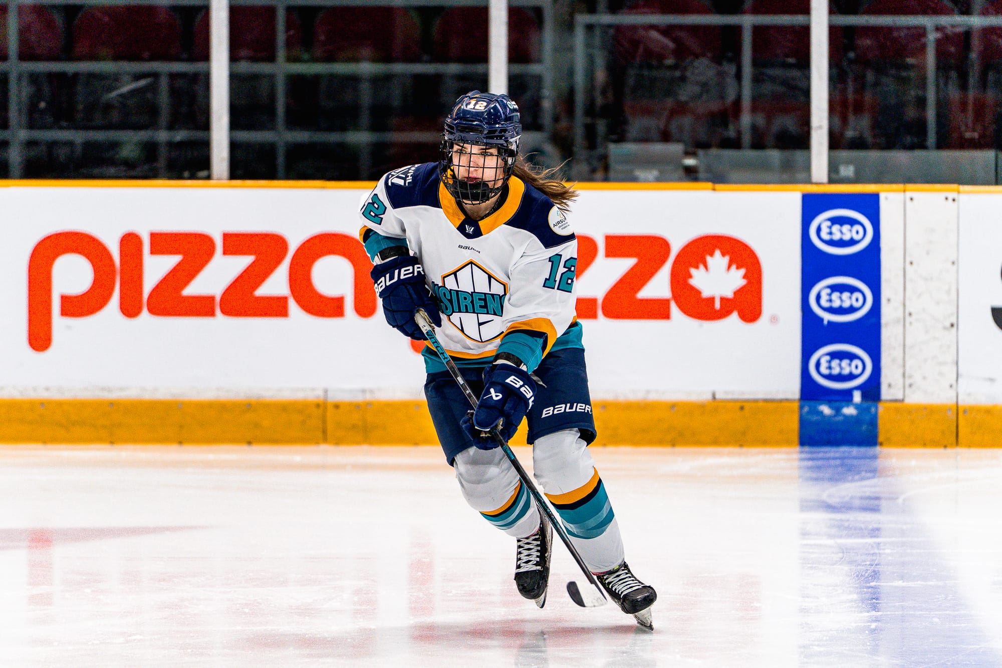 Aurard looks up as she skates toward a play. She is wearing a white away uniform.