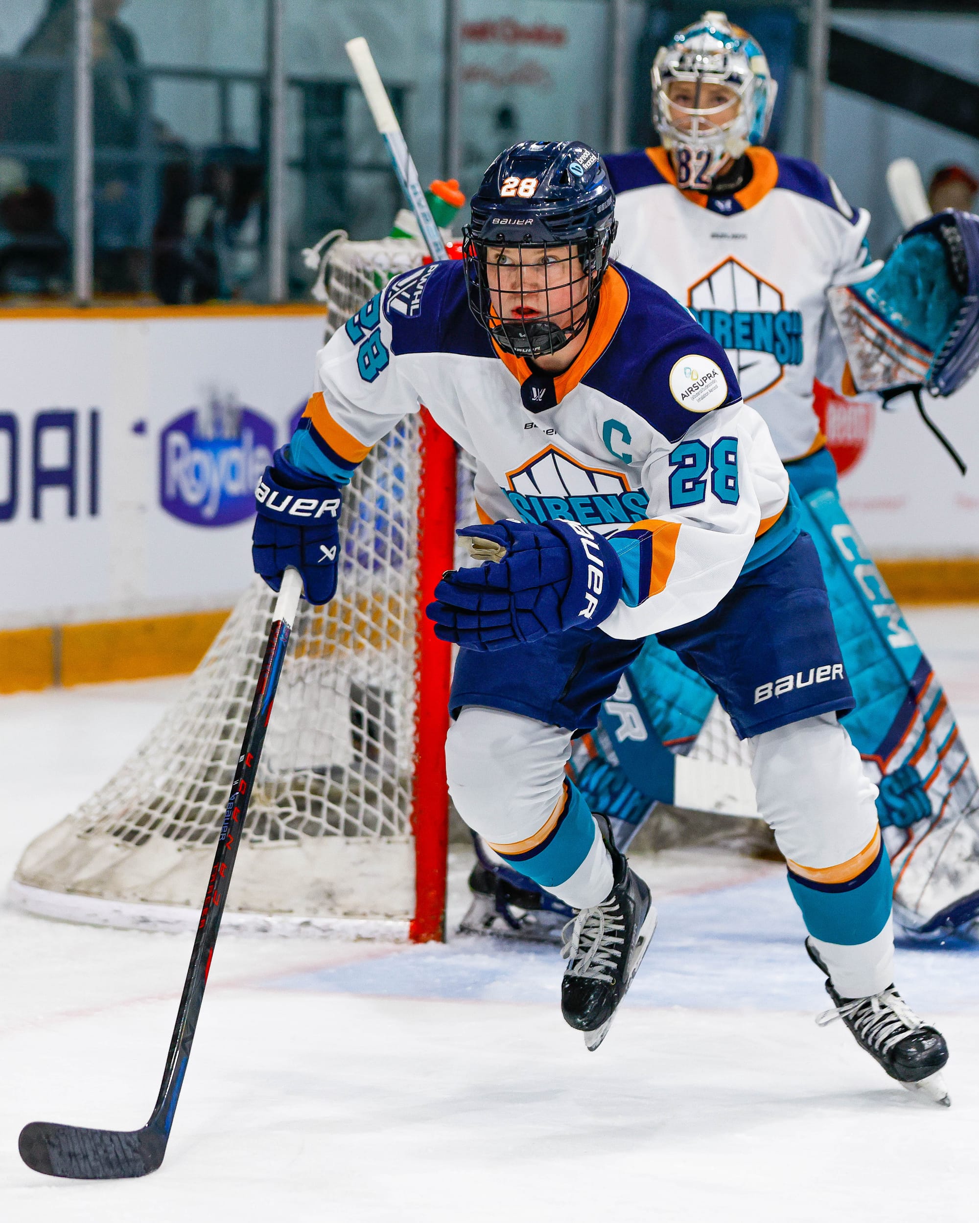 Zandee-Hart pushes off as she begins to skate toward the play, which is out of frame. She is wearing a white away uniform.