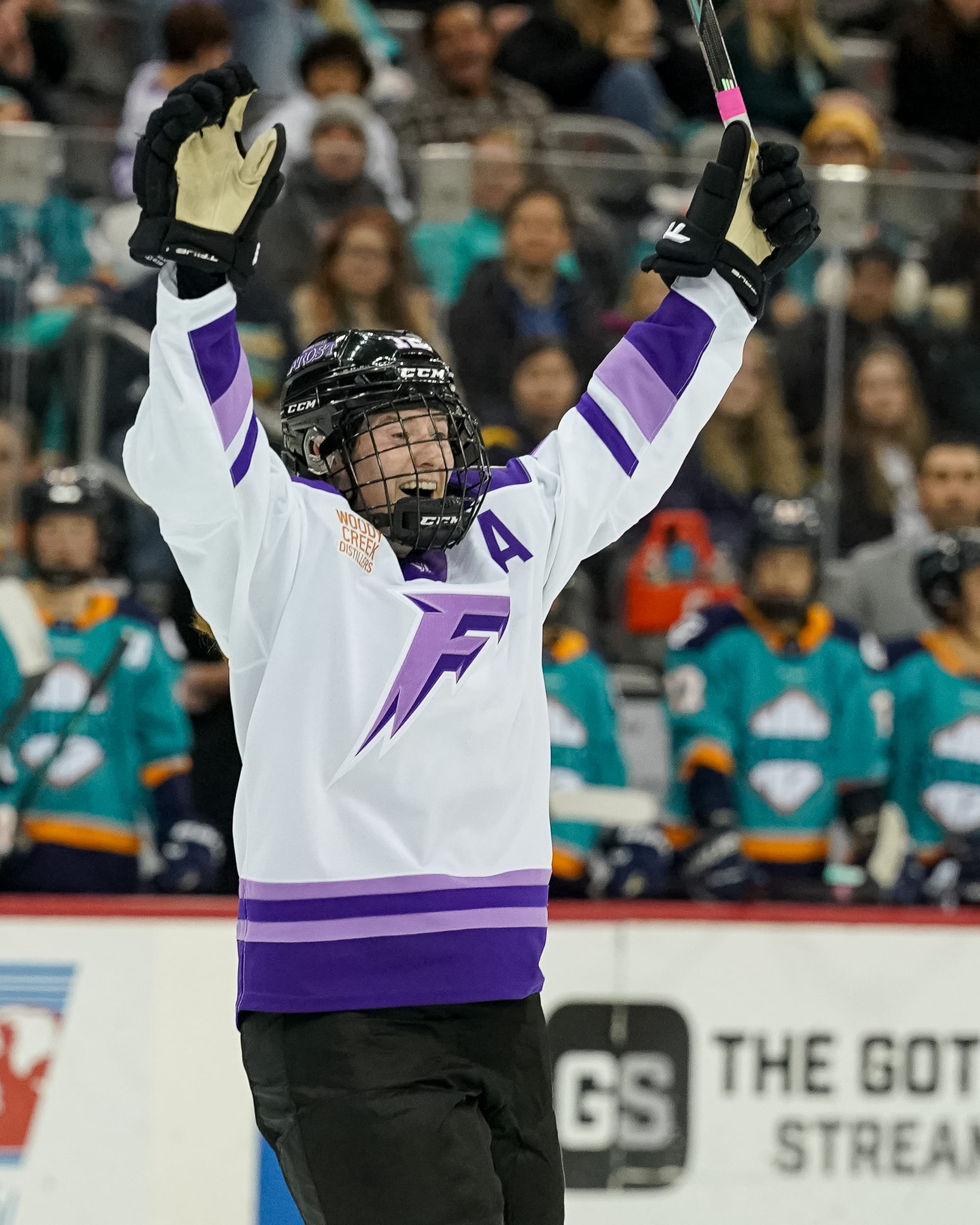 Pannek raises both arms above her head and smiles. She is wearing a white away uniform.