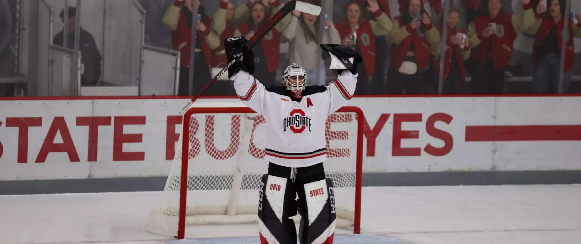 Thiele stands at the top of her crease with her arms raises above her head in celebration. She is wearing a white OSU uniform.