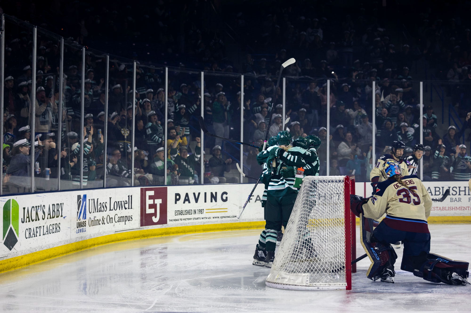 Fleet players celebrate a goal to the left of Desbiens' crease. The Fleet are wearing green home uniforms, while the Victoire are in cream away ones.