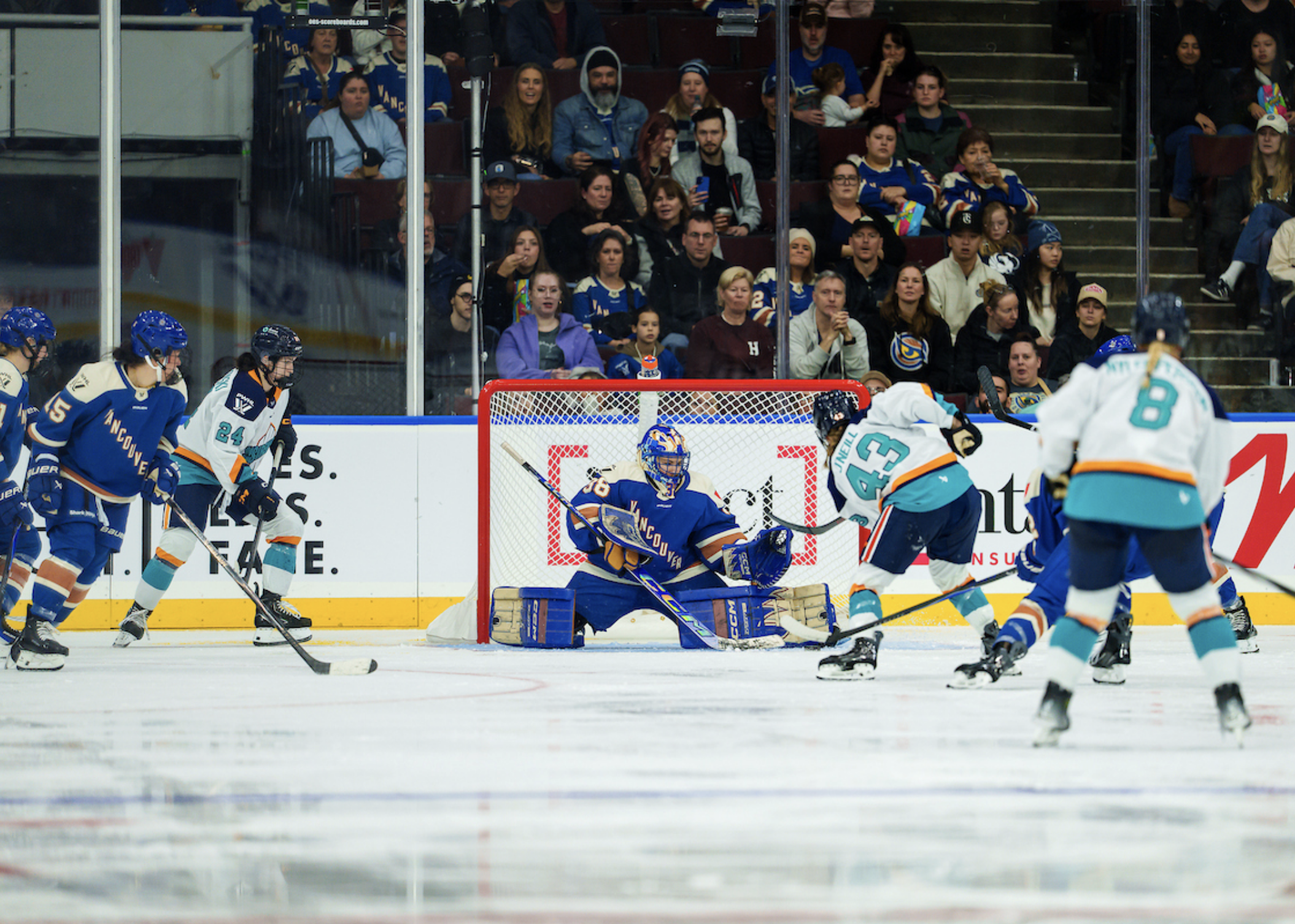 O'Neill takes a shot on Maschmeyer as two teammates come in to support and Vancouver players try to defend. The New York players are in white away uniforms, while Vancouver is wearing blue home ones.
