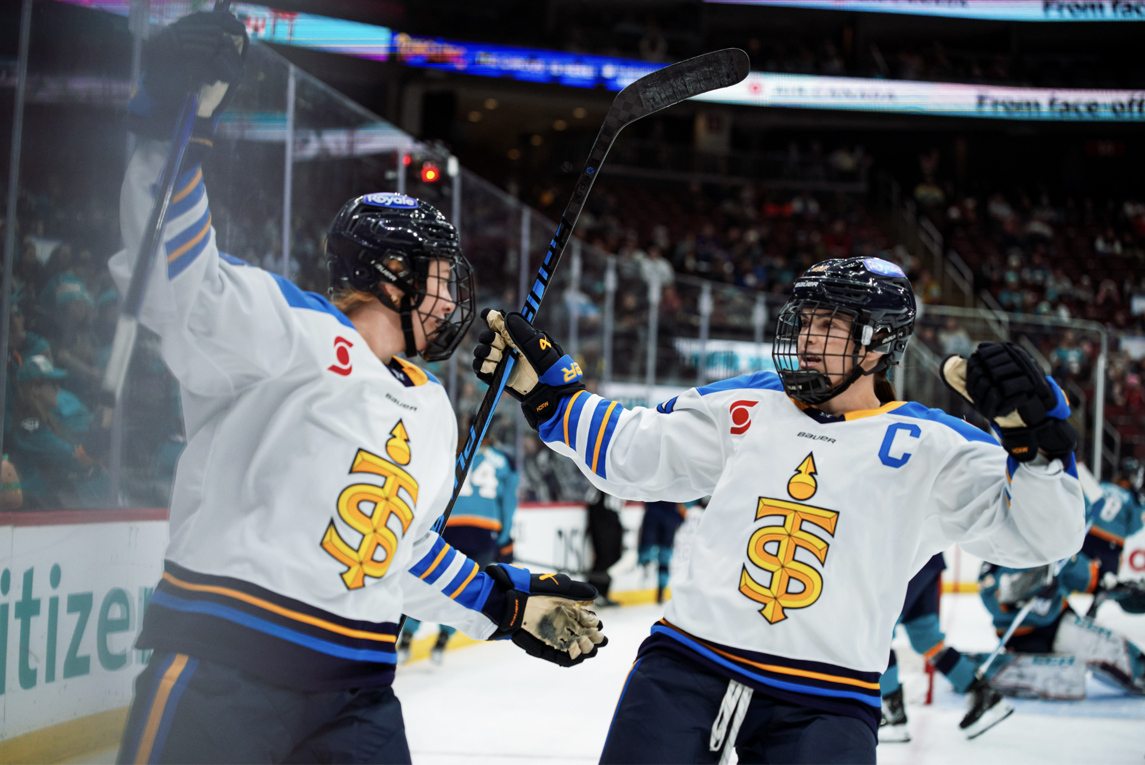 Two Toronto players open their arms wide as they are about to embrase in the corner after scoring. They are both wearing white away uniforms.