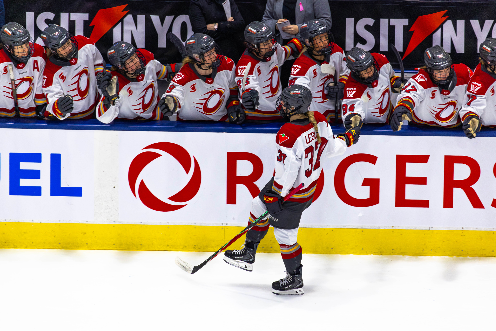Leslie skates down the handshake line at the bench after scoring against Toronto. She and all of her teammates are wearing white away uniforms.