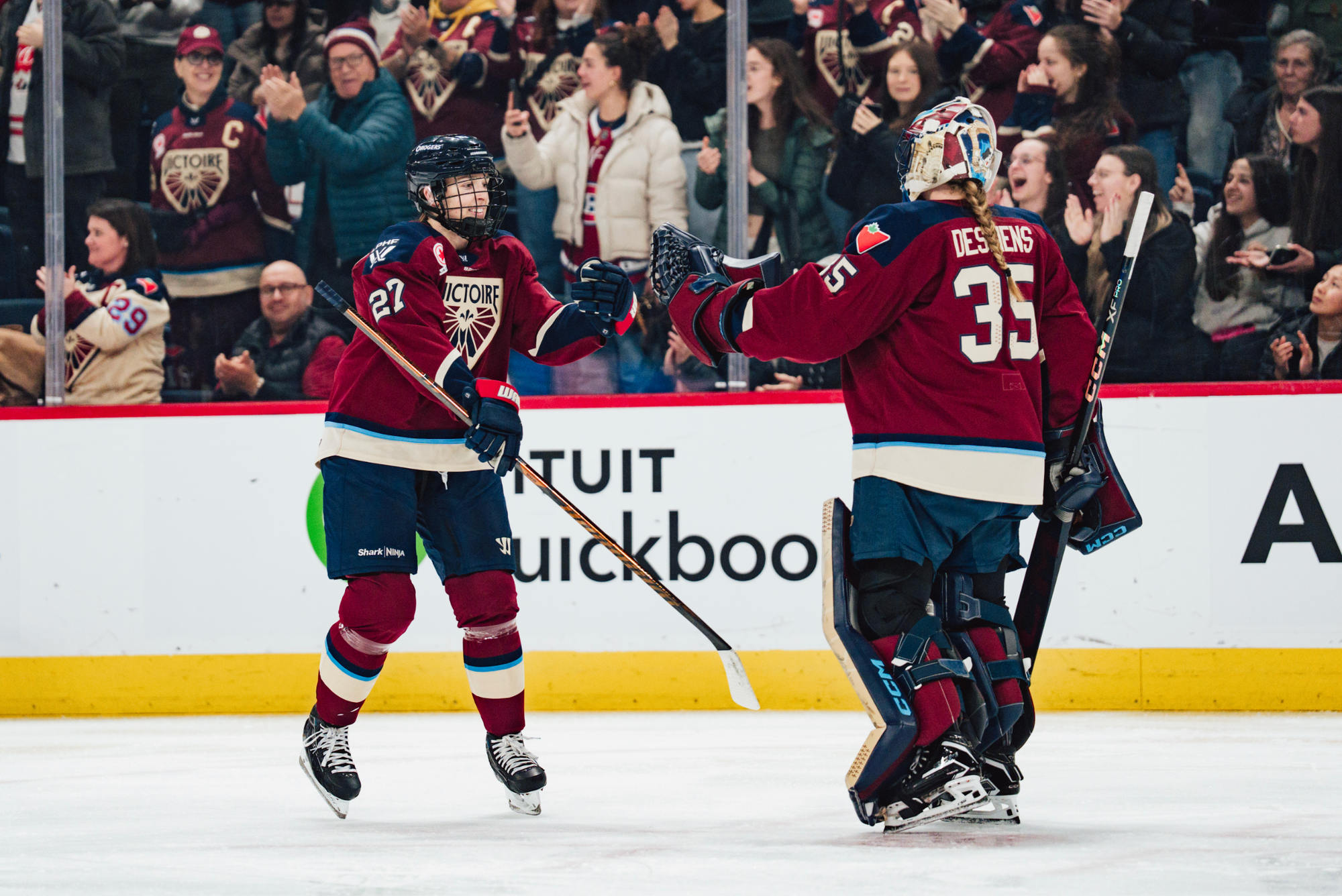 arkangelo and Desbiens exchange a smile as they go to fist-bump each other following Darkangelo’s goal. They are both wearing maroon home uniforms.