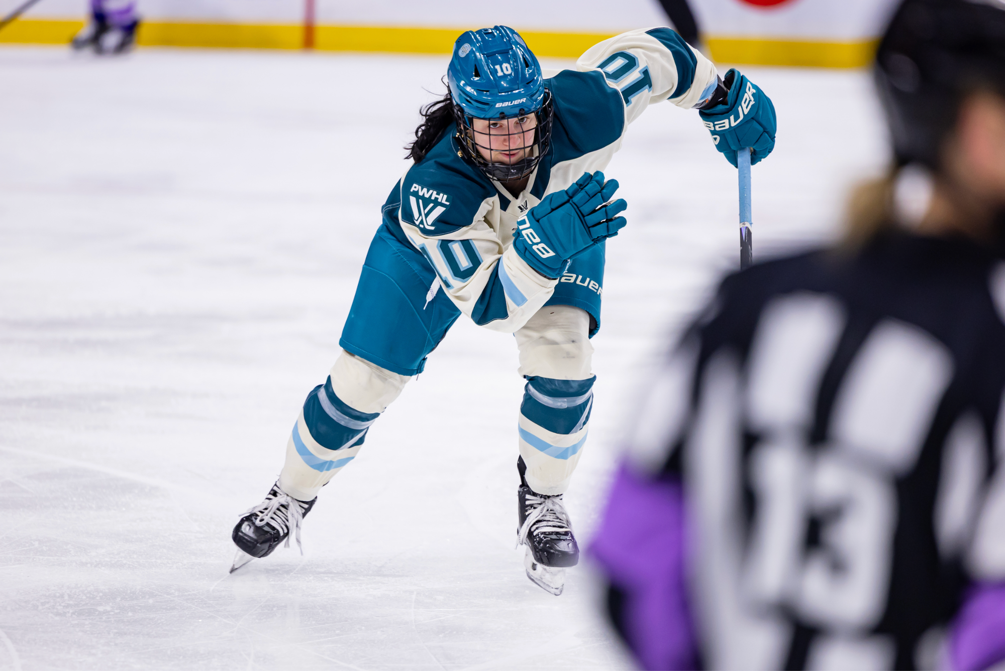 Buglioni skates hard towards a play out of frame. She is wearing a cream away uniform.