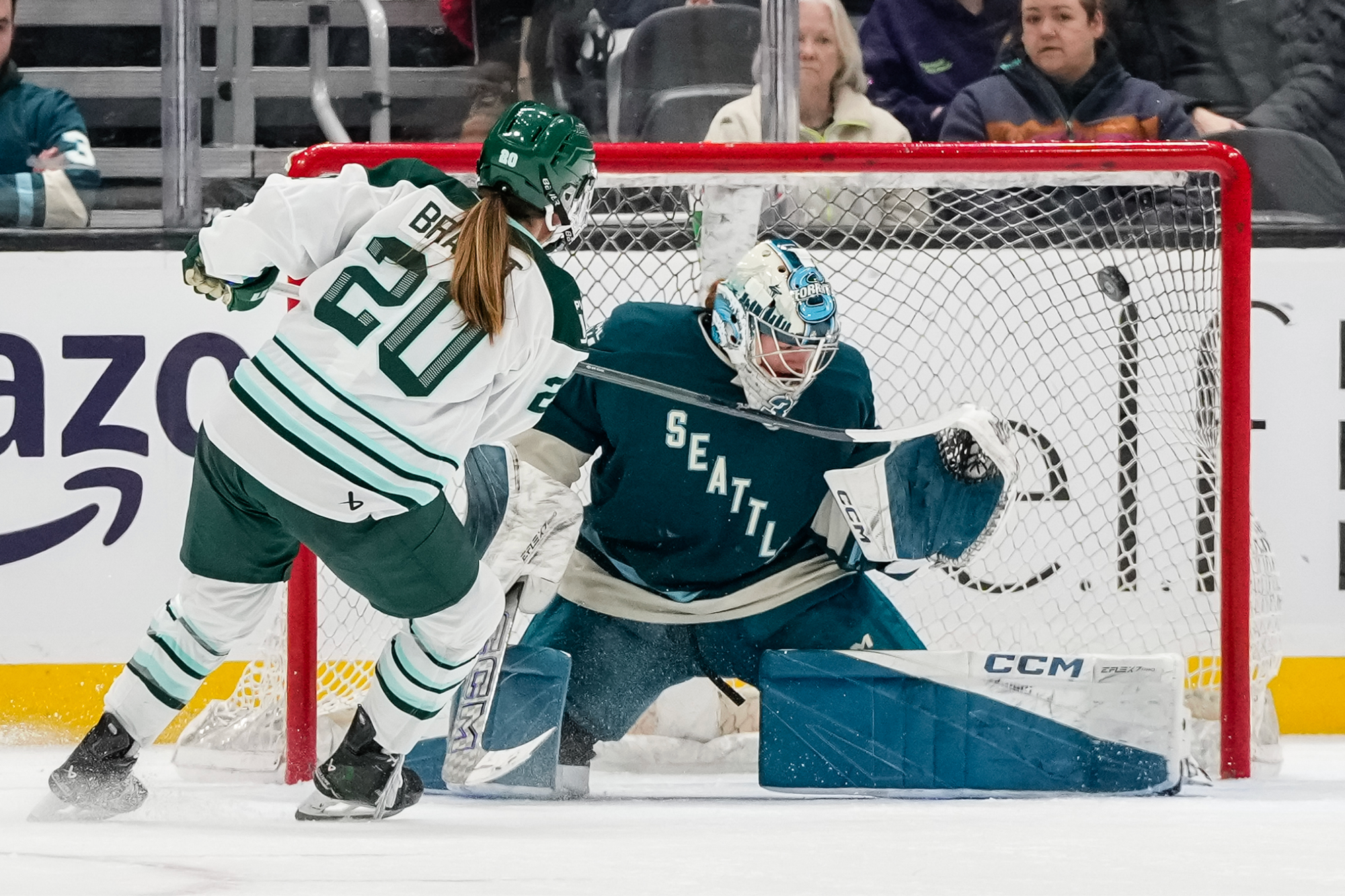 Brandt pots a goal into the top corner after Schroeder drops to her knees to try to make the save. Brandt is wearing a white away uniform, while Schroeder is in a teal home one.