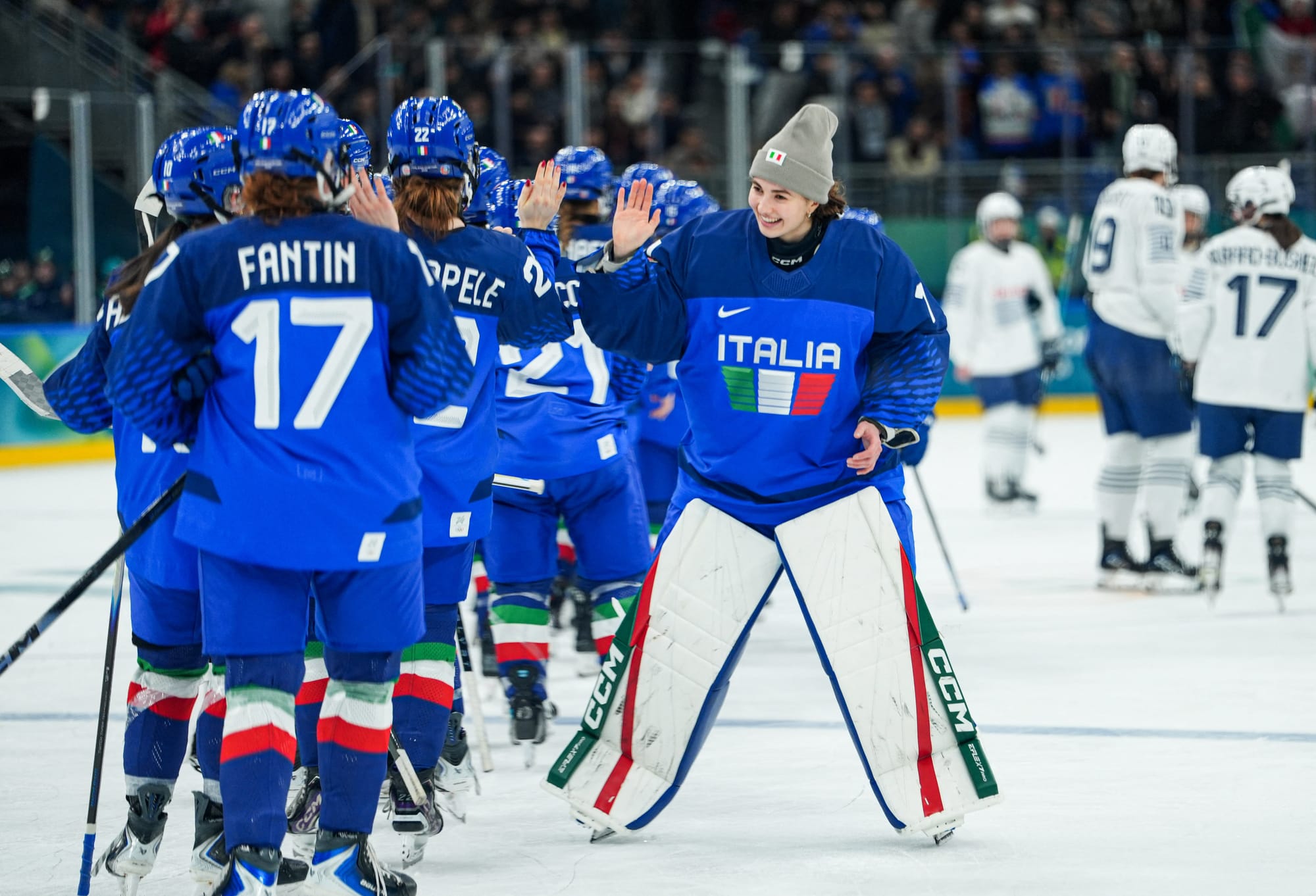Durante smiles and high fives her teammates after their win over France. They are all wearing blue home uniforms.