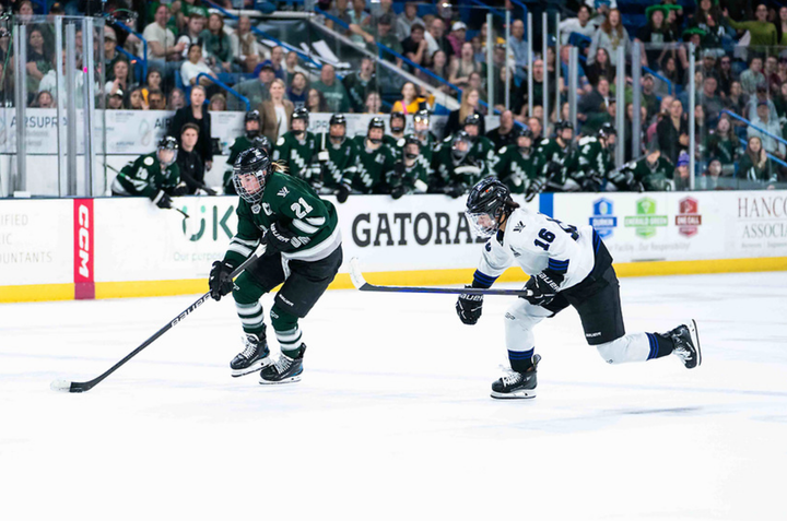 Knight (left in green) enter the zone and drives the net with the puck while Jaques (right in white) chases.