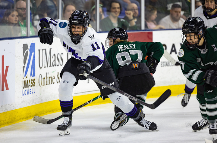 Kunin skates away from a battle with Healey behind the net. She is wearing white, while Healey is kneeling in green.
