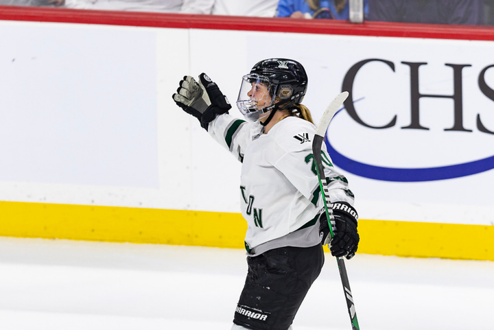 Brandt extends her arms in preparation for a celebratory hug following a win. She is wearing a white away uniform.
