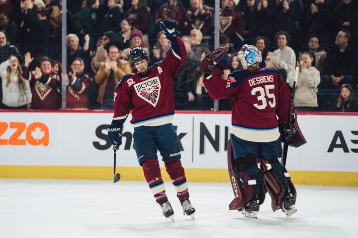 Stacey (left, facing camera) and Desbiens (right, facing away) fistbump on the ice. Both are wearing maroon home uniforms.
