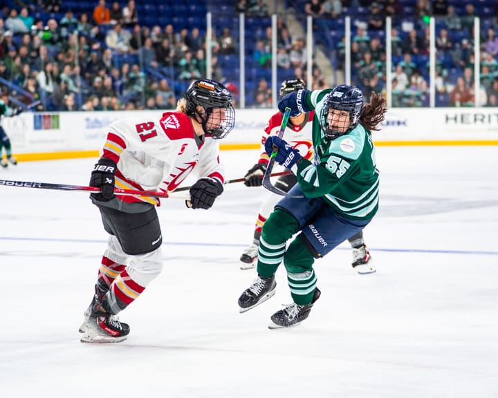 Pejšová (right in green) hunts the puck as Bell (left in white) tries to defend her.