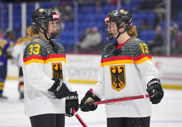 Lilli (left) and Luisa (right) stand near the blue line having a discussion. They are wearing away Germany uniforms.