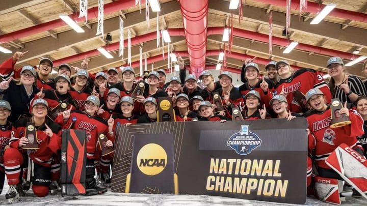 The UWRF team poses with the championship trophies and banner, dressed in their away red uniforms..