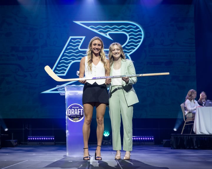 Huber and Marmer smile and hold a wooden stick with "2025 PWHL Draft" and "Boston Fleet" printed on it.