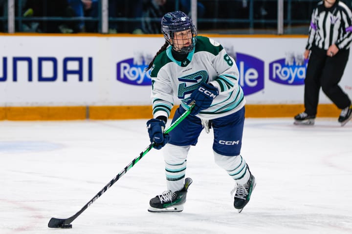 Babstock looks to her left as she skates with the puck during a PWHL game. She is wearing a white away uniform.