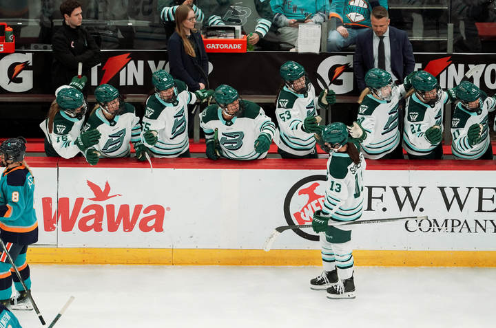 Schepers skates down the handshake line at the bench. She and her teammates are all winning white away uniforms.