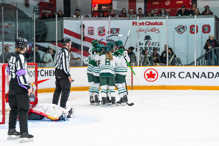 Fleet players celebrate a goal with a tight group hug. They are all wearing white away uniforms.